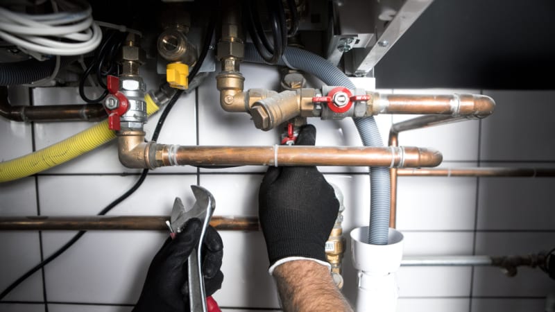 Hands of Plumber with a wrench when you may need certain plumbing services